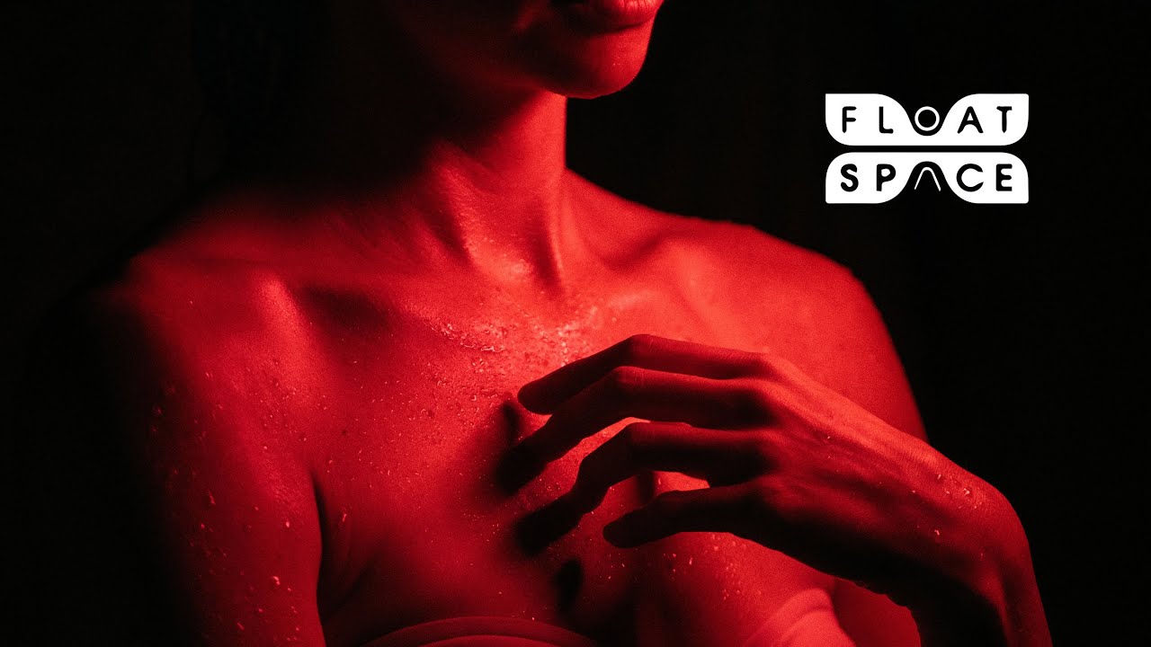 A person relaxes inside a softly lit float therapy space.