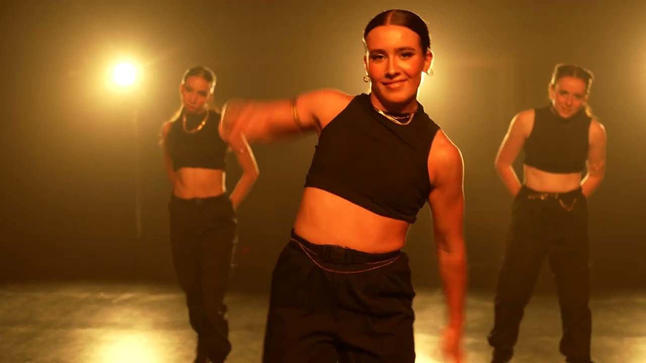 A dance ensemble performs in red light inside a cinematic industrial location.